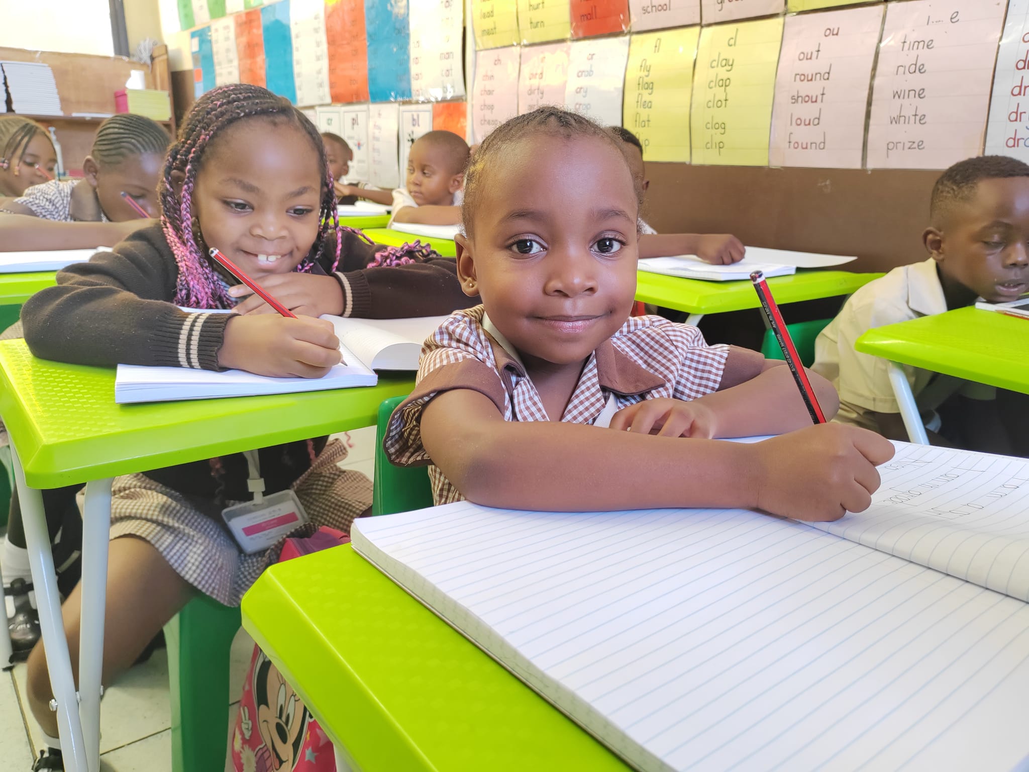 Two young learners completing written work in class