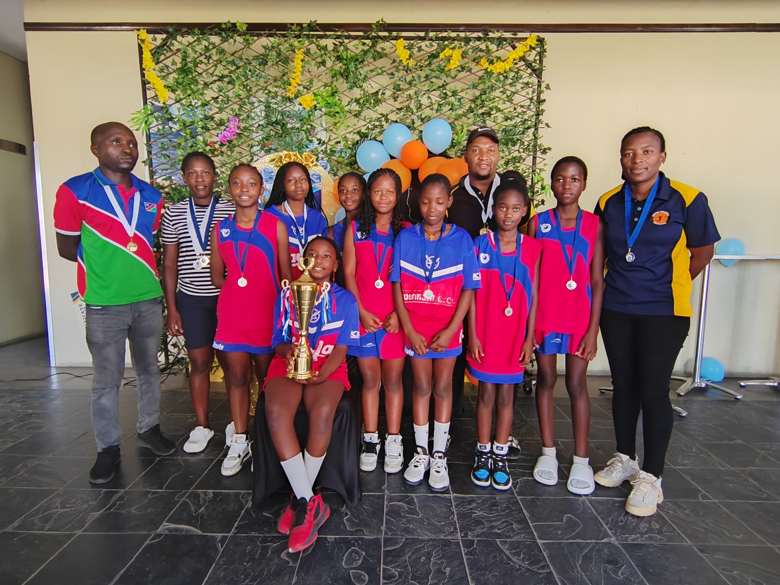 School netball team posing with their coaches
